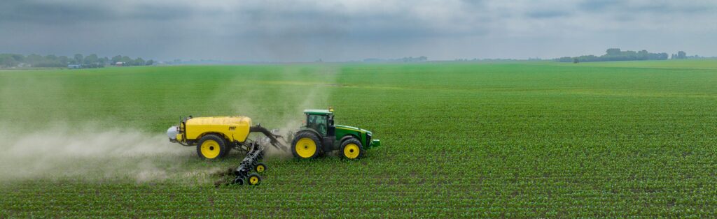 Foto: Tractor bespuit een veld met jonge groenteplantjes